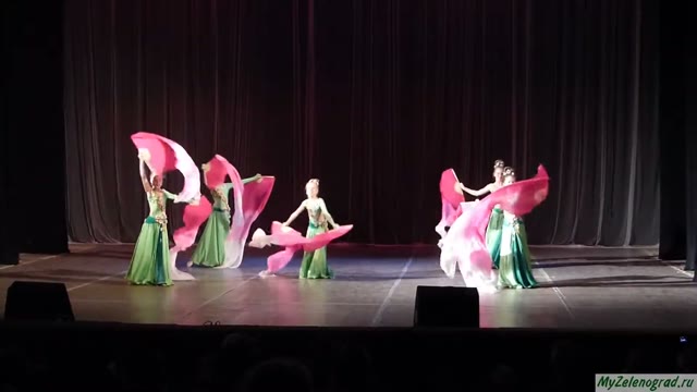 Группа танцовщиц с розовыми веерами на сцене